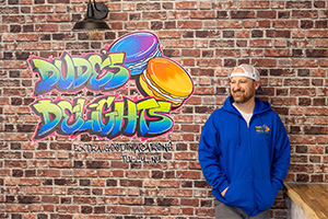 Roger Dudes standing infront of  mural of Dudes Delights