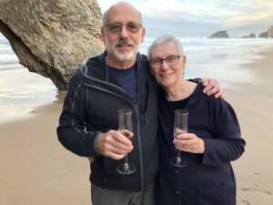 Lewis and Sally cutler on a beach with wine glasses
