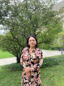 Dr. Mercy Borbor-Córdova in a floral dress standing in front of a tree