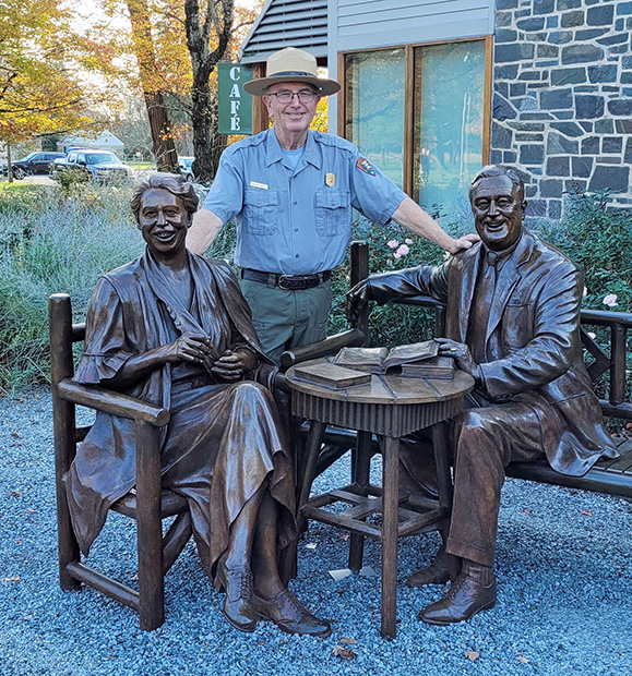 David Hayes standing with two statues