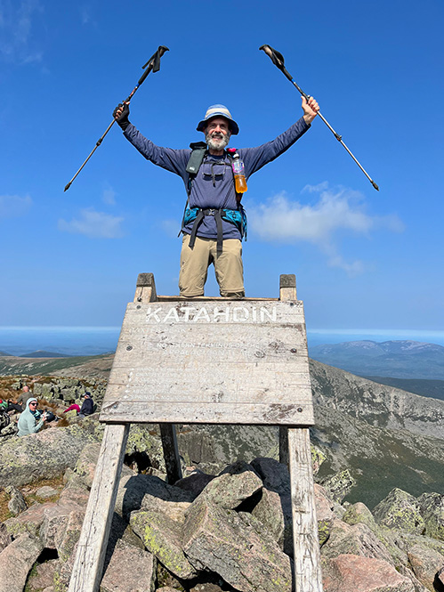 Gerry Madigan on top of mountain Katahdin holding his walking sticks